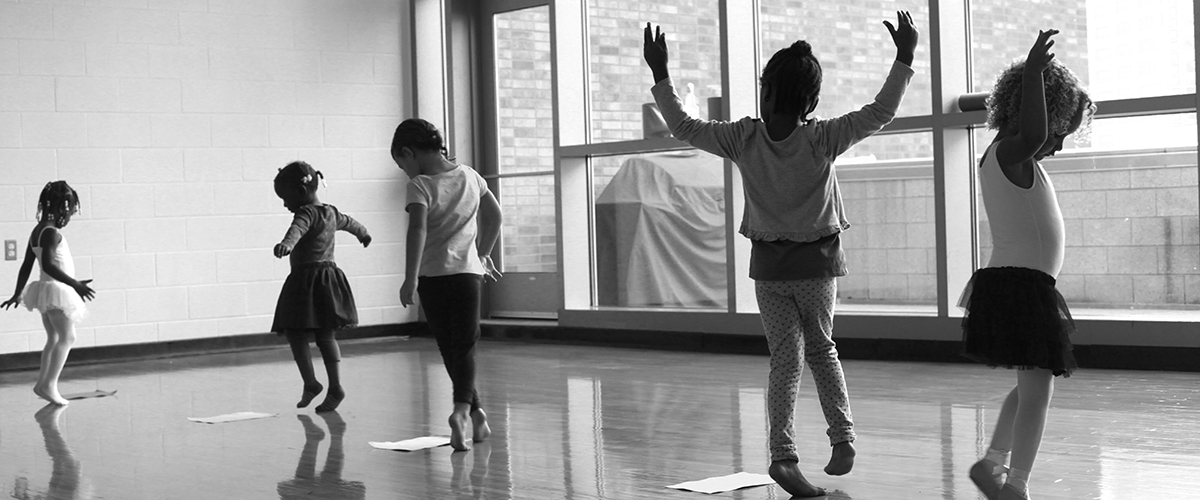 youth dance - a black and white photo of children dancing inside a room