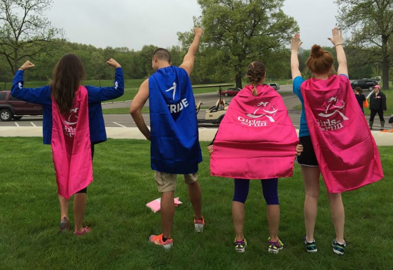 superheroes at a YMCA Girls on the Run 5K - a photo of 4 people with red and blue capes at the back 