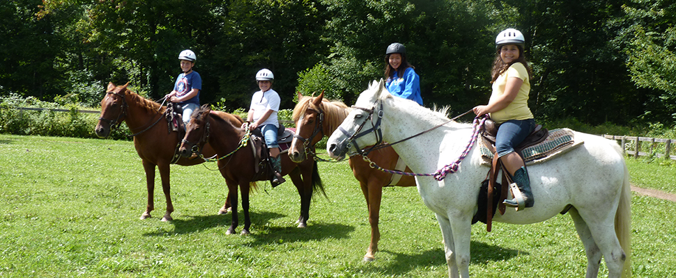 a photo of 4 people smiling while riding a horse