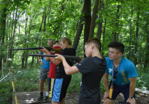 a picture of children in a forest practicing on how to hold a gun