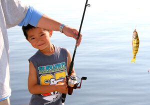 a photo of a boy smiling while a fish is being caught
