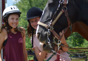 two girls smiling in front of a horse