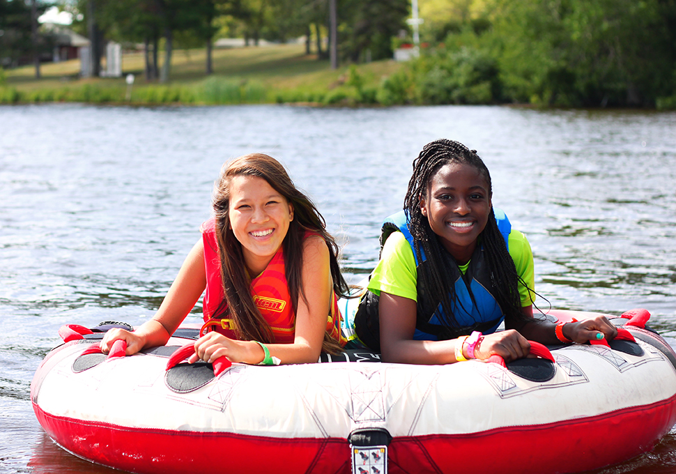 a photo of two girls smiling while riding  on a floater