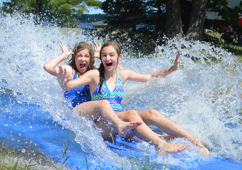 a photo of two girls enjoying the slide in a swimming area
