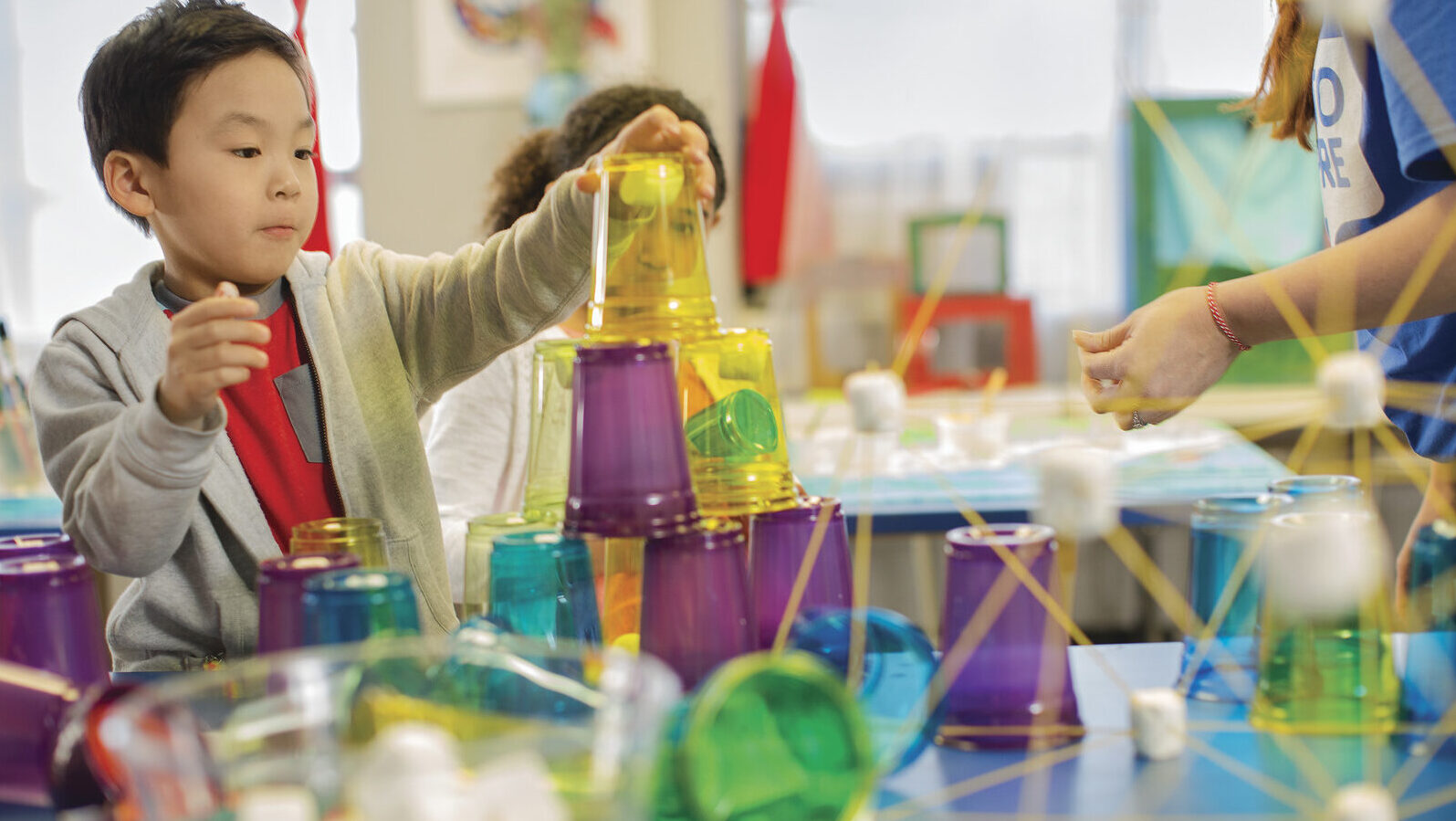 fun YMCA programs - a picture showing children making experiments and playing with colored plastic cups