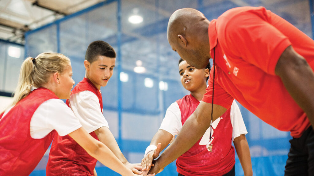 Youth Sports at the Y - a group of boy basketball team putting their hands together in the middle forming a circle