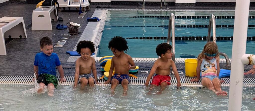 children sitting on the edge of the Boll Family YMCA indoors pool