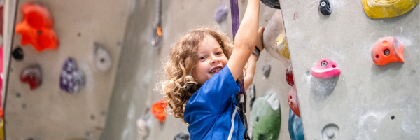 a kid in a blue shirt climbing a rock wall